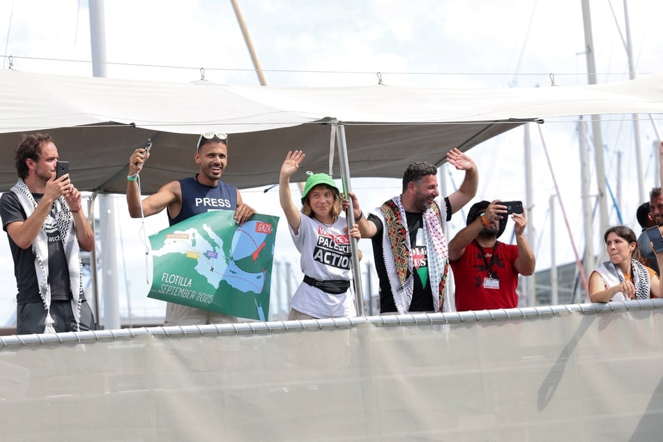 Greta Thunberg (third from l.) and other activists wave as their Gaza aid boat leaves the port of Barcelona on August 31, 2025.