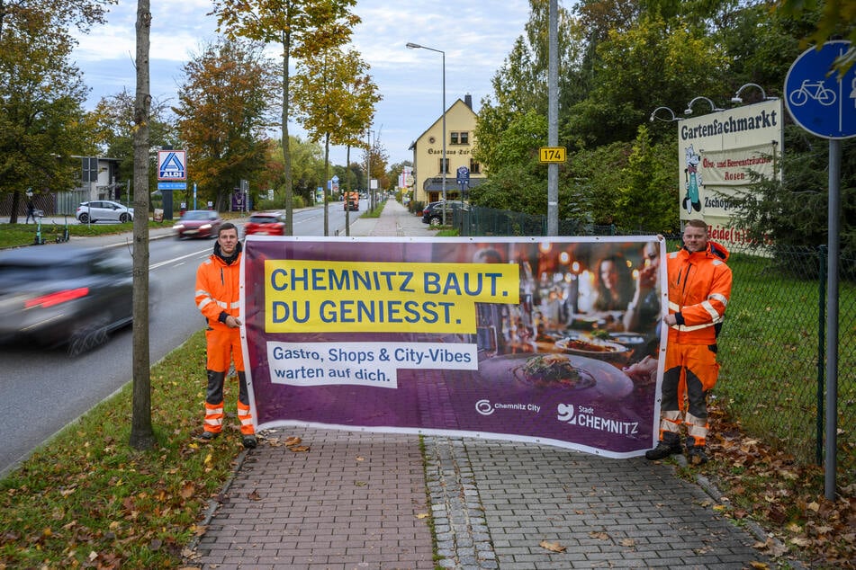 Die Azubis Ron-Myguel Melzer (17, l.) und Lennox Schätzler (19) aus dem Tiefbauamt zeigen eines der Werbeplakate an der Zschopauer Straße. Insgesamt gibt es vier Motive.