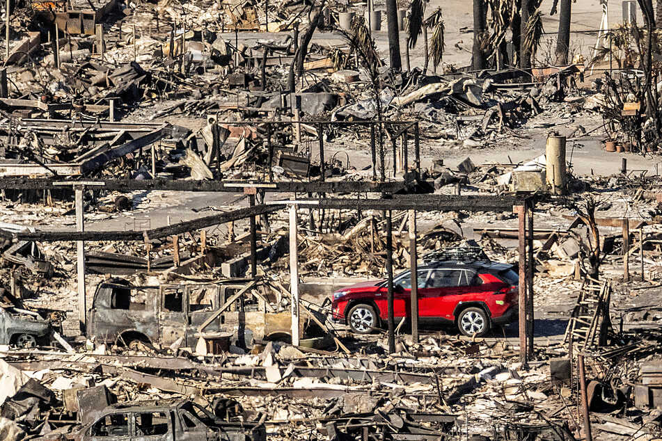 Ein Auto fährt an Häusern und Fahrzeugen vorbei, die durch das Palisades-Feuer in den Pacific Palisades Bowl Mobile Estates zerstört wurden.