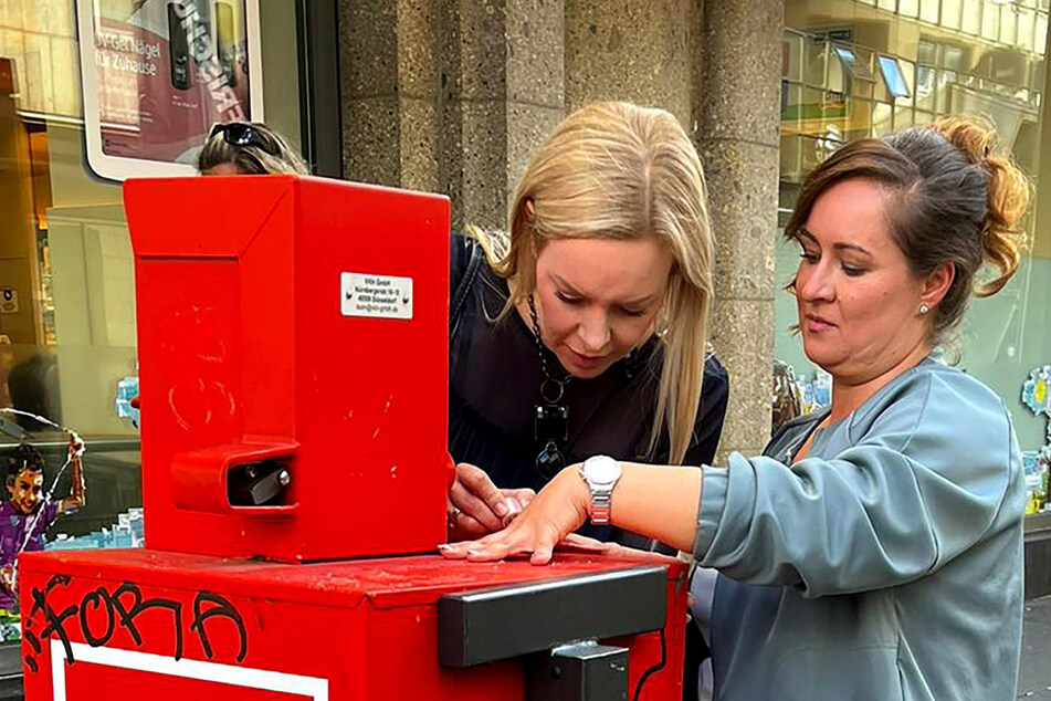 Isabel Edvardsson (40, l.) legt selber Hand an und lackiert Margos Fingernägel auf einem Zeitungsautomaten.