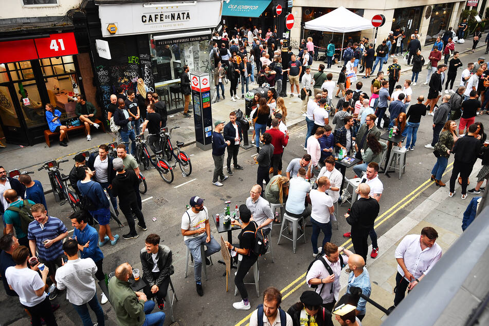 Menschen versammeln sich zum gemeinsamen Trinken auf einer Straße vor Bars im Stadtteil Soho. Pubs waren in England für über drei Monate geschlossen.
