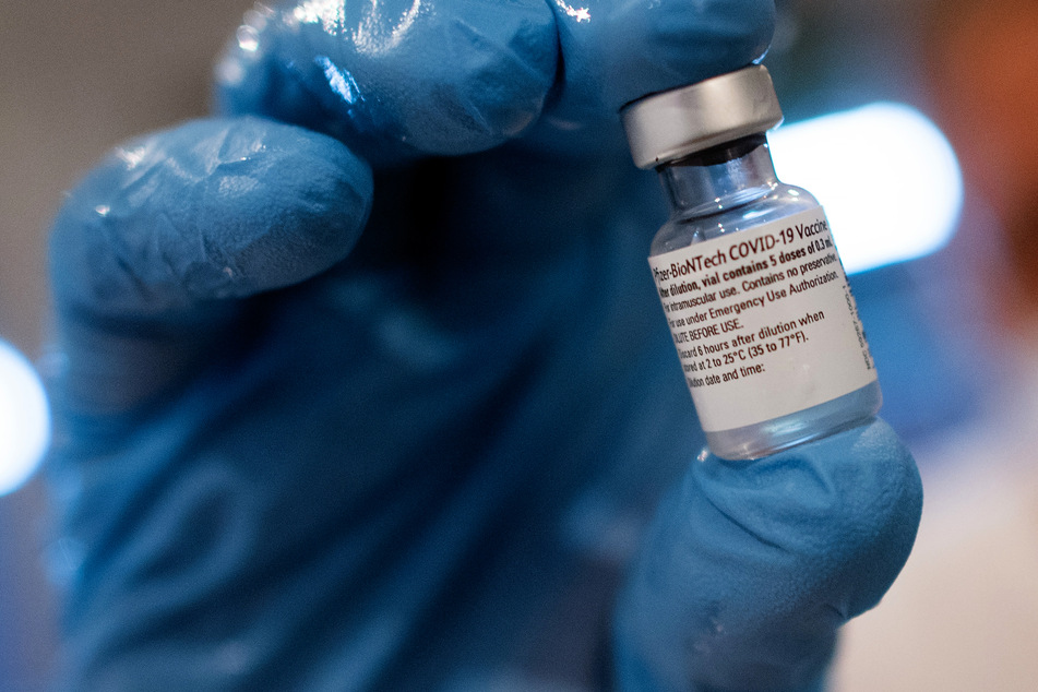 Ein Arzt hält im Impfzentrum Düsseldorf ein Gläschen mit dem Impfstoff von Biontech/Pfizer in der Hand, mit dem er Menschen gegen das Coronavirus impft.