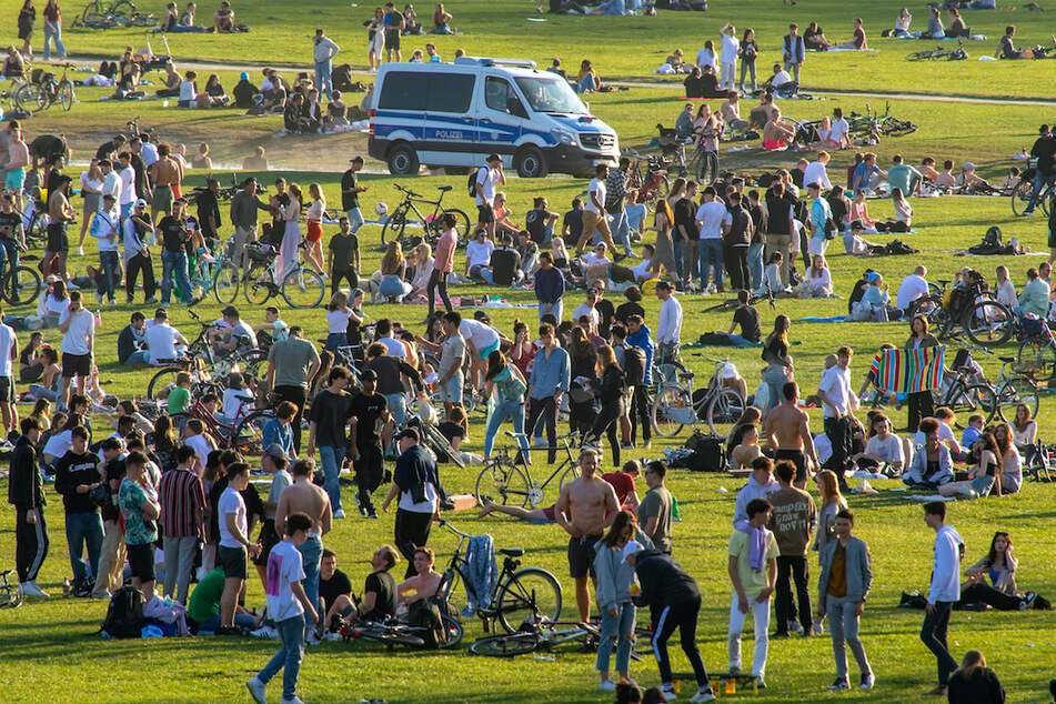 Polizisten fahren Streife im Englischen Garten, wo Hunderte von Menschen auf der großen Wiese nahe dem Monopteros den sonnigen Frühlingstag mit warmen Temperaturen verbringen.