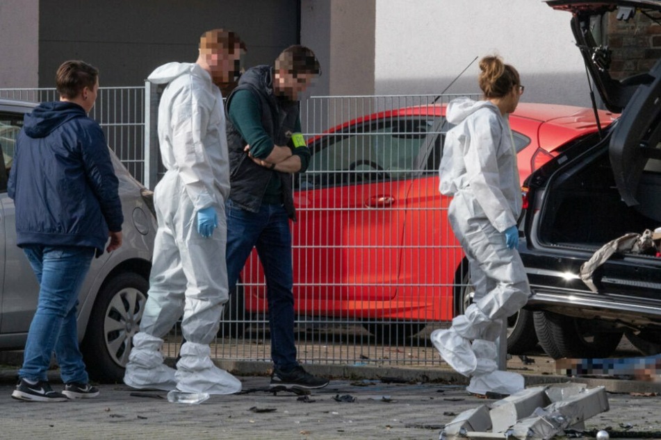 Mitarbeiter der Spurensicherung stehen in Limburg an dem Wrack eines dunklen Autos, unter dem die Leiche einer Frau liegt.