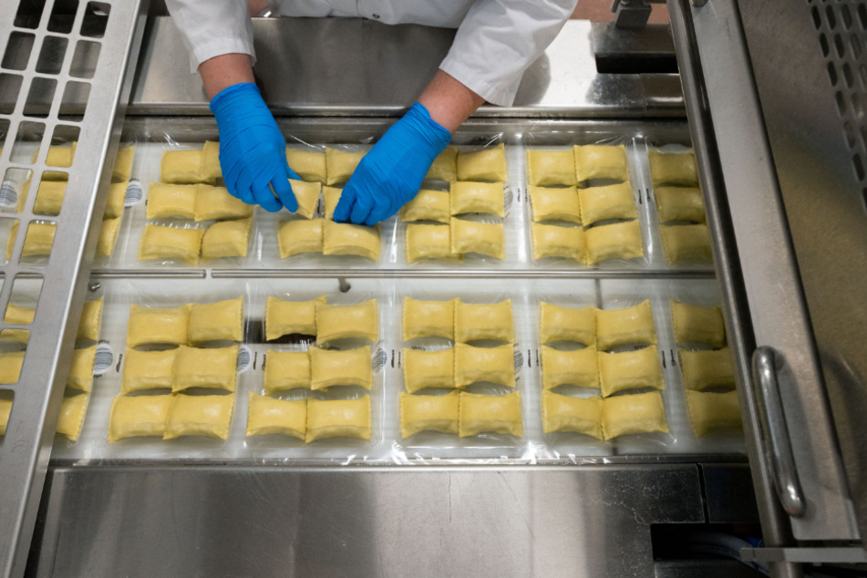 Eine Mitarbeierin des Teigwarenproduzenten Bürger GmbH & Co. KG richtet Maultaschen in der Verpackung aus.