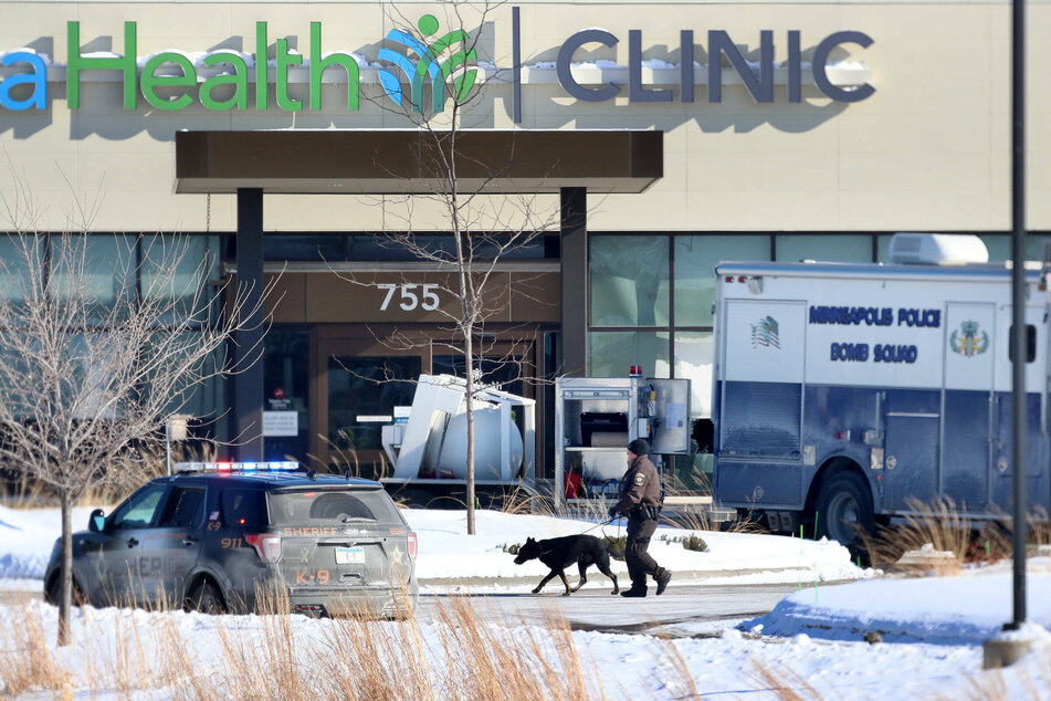 Officers with dogs search the parking lot outside of the scene of a mass shooting at the Buffalo Allina Health Clinic.