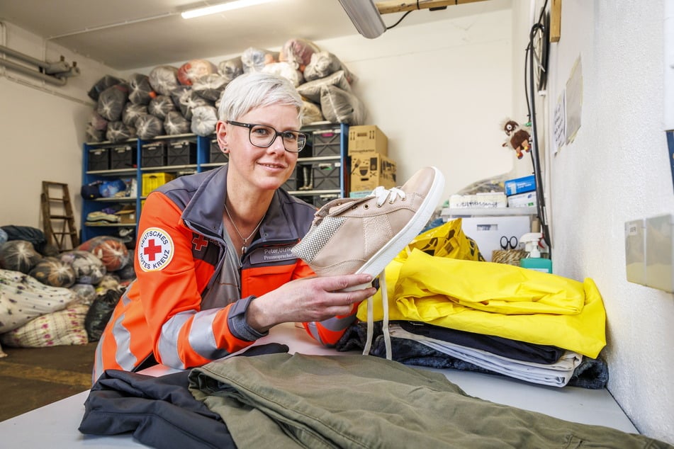 Ulrike Peter (44) vom DRK zeigt ein Paar Schuhe, das sie als Spende erhalten hat. Es wird im Pieschener Geschäft für einen kleinen Taler verkauft.