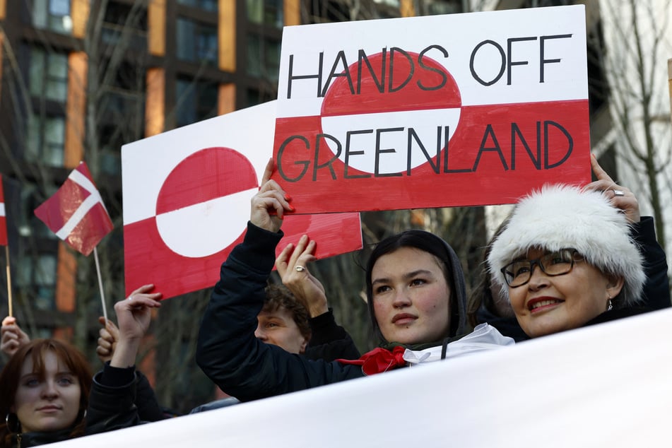 People wave flags and raise signs as they take part in a demonstration against Donald Trump's plan to take Greenland, outside the US Embassy in London on January 24, 2026.