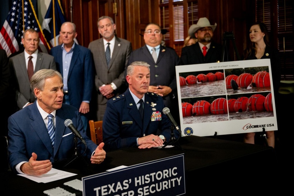 Texas Governor Greg Abbott (l.) speaks about an illustration of new "border security" measures during a news conference at the State Capitol on June 8, 2023.