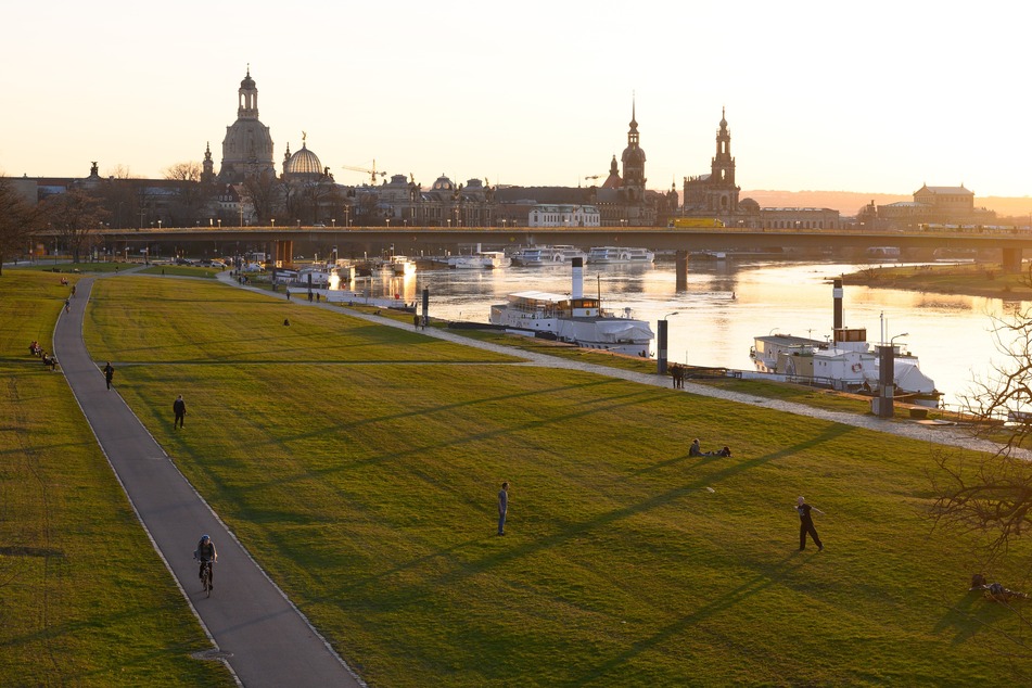 Menschen verbringen ihre Zeit am Ufer der Elbe vor der Kulisse der Altstadt.