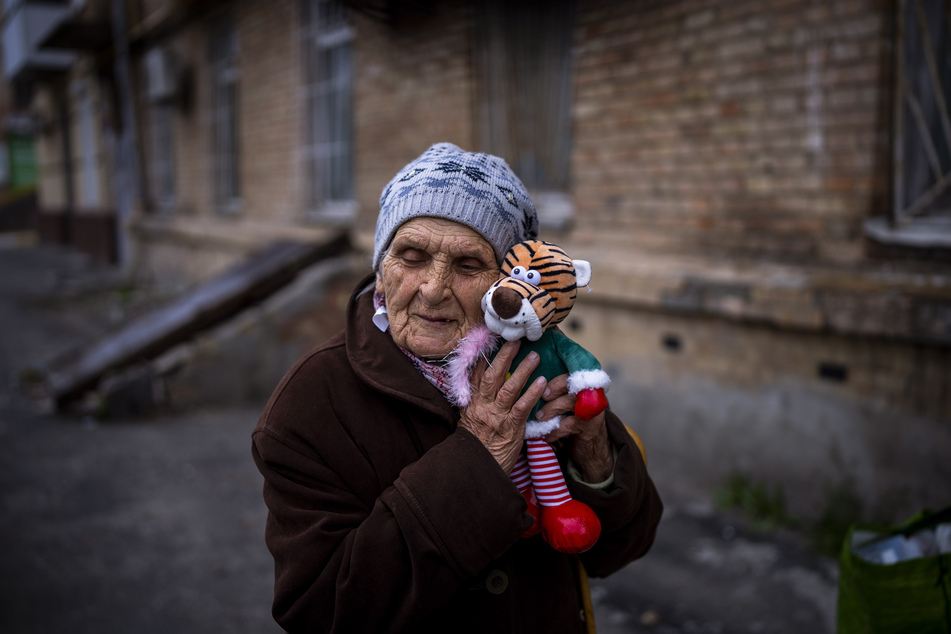 Melaniya Kovalenko umarmt vor ihrem Haus in Butscha ein Kuscheltier, welches sie geschenkt bekam hat und an ihre Enkeln weitergeben möchte. Kovalenko wurde während des Holodomor geboren, erlebte als Teenager den Zweiten Weltkrieg und überlebte nun die russische Besatzung von Butscha.