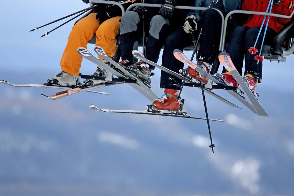 Skifreunde mit Abfahrtski fahren mit der Vierersesselbahn rauf auf den Fichtelberg.