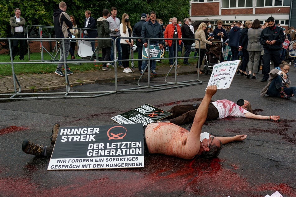 Klimaaktivisten liegen mit Kunstblut übergossen auf dem Boden. "Verrechnet Herr Laschet. 2 Grad Klimaerwärmung waren zu viel", steht auf einem der Plakate.