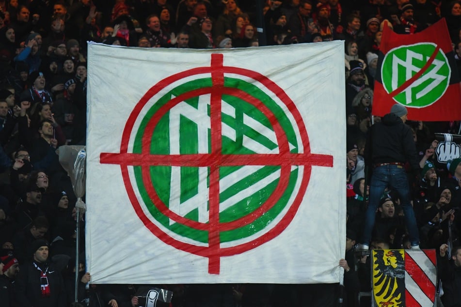 Nürnberger Fans halten ein Banner mit dem Logo des DFB in die Höhe, das in einem Fadenkreuz zu sehen ist.
