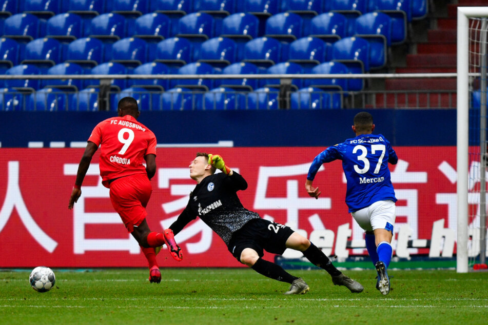 S04-Keeper Markus Schubert (M.) wird in der Nachspielzeit von Augsburgs Sergio Cordova (l.) umkurvt, der danach zum 3:0 für den FCA einschiebt. Münir Mercan hatte den Ball davor als letzter Mann verstolpert.