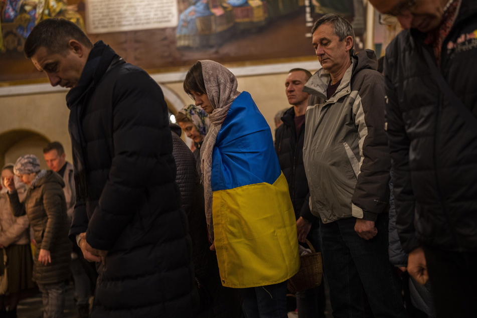 Eine mit der ukrainischen Flagge bedeckte orthodoxe Christin nimmt an einer Ostermesse in Kiew teil. Millionen orthodoxe Christen in aller Welt haben in der Nacht zum Sonntag mit großen Mitternachtsmessen das Osterfest eingeläutet.