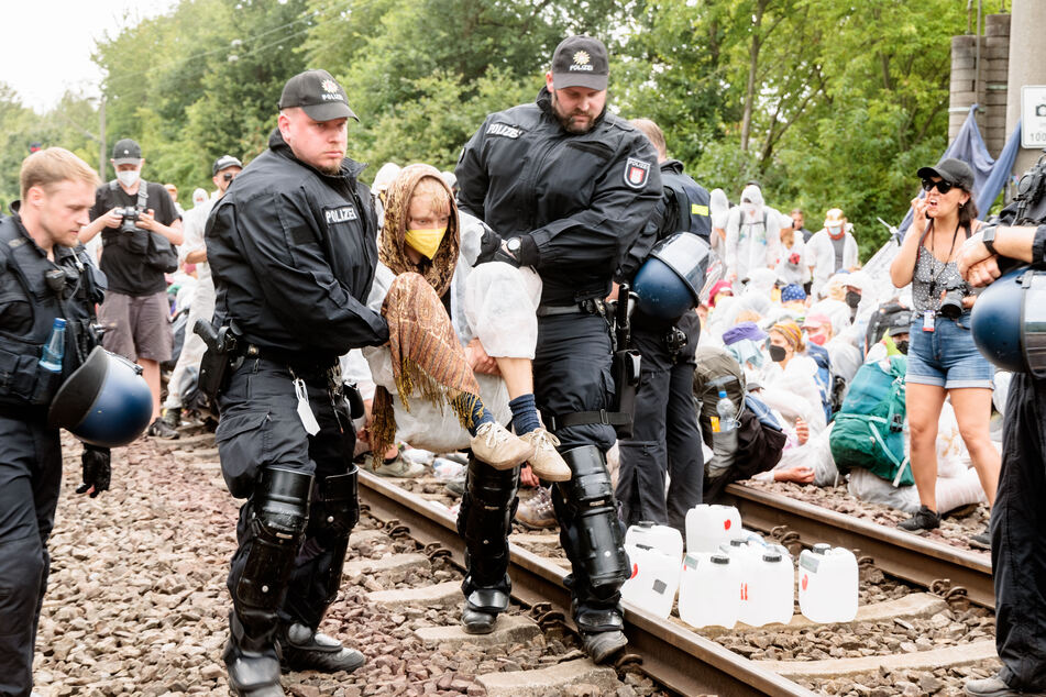 Klima-Aktivisten die aus Protest Gleise im Hamburger Hafen besetzt haben, werden einzeln von Polizeibeamten von den Gleisen getragen.