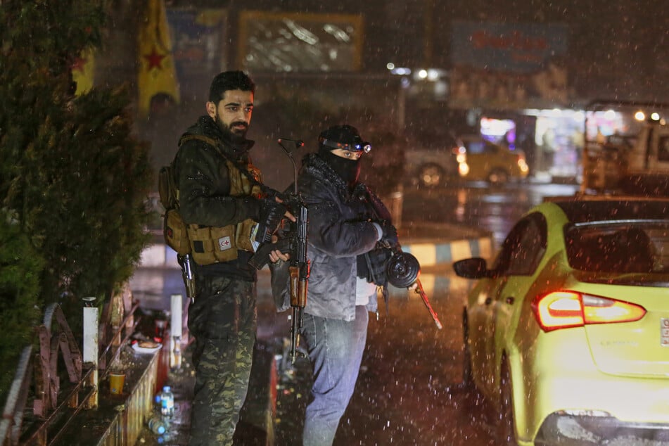 Bewaffnete kurdische Freiwillige stehen während einer nächtlichen Patrouille an einem Kontrollpunkt Wache. (Archivbild)