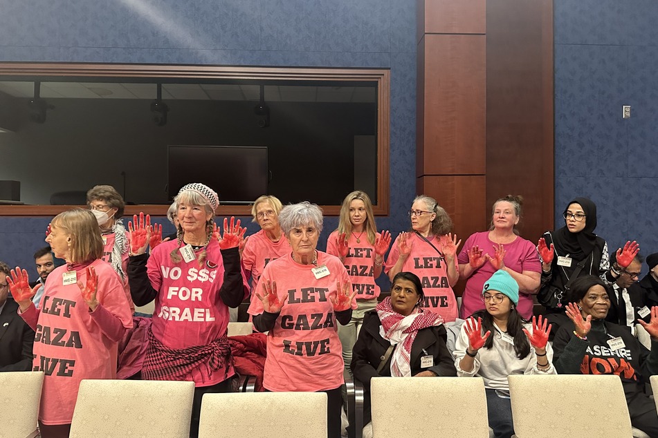 During the hearing, CODEPINK activists raise their hands, painted red to symbolize the blood US government officials have on their hands.