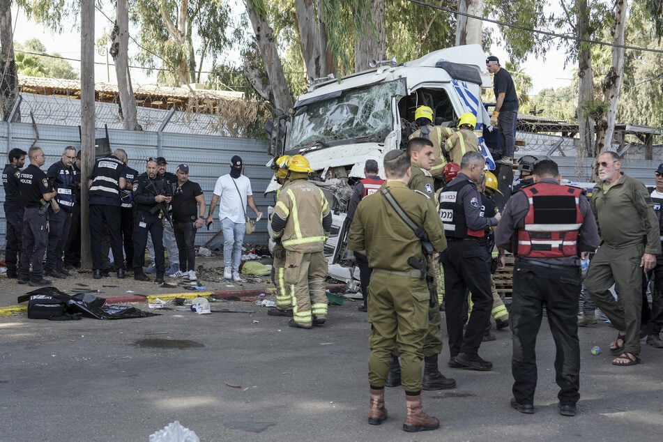 Israelische Polizisten klettern auf einen Lastwagen, um die Leiche eines Fahrers zu untersuchen, der eine Bushaltestelle in der Nähe des Hauptquartiers der israelischen Spionagebehörde Mossad gerammt und dabei Dutzende von Menschen verletzt hat.