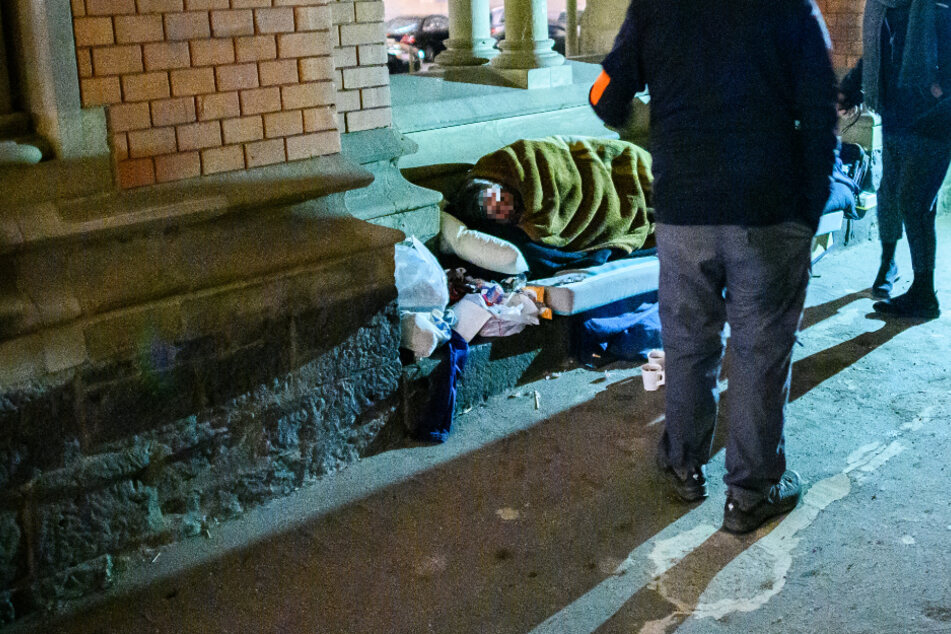 Sozialarbeiter schauen nach einem Mann, der im Durchgang einer Frankfurter Kirche schläft.