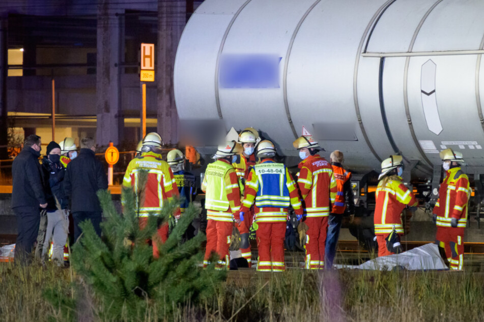 Rettungskräfte und Ermittler stehen neben den abgedeckten Leichen am Kesselwagen.