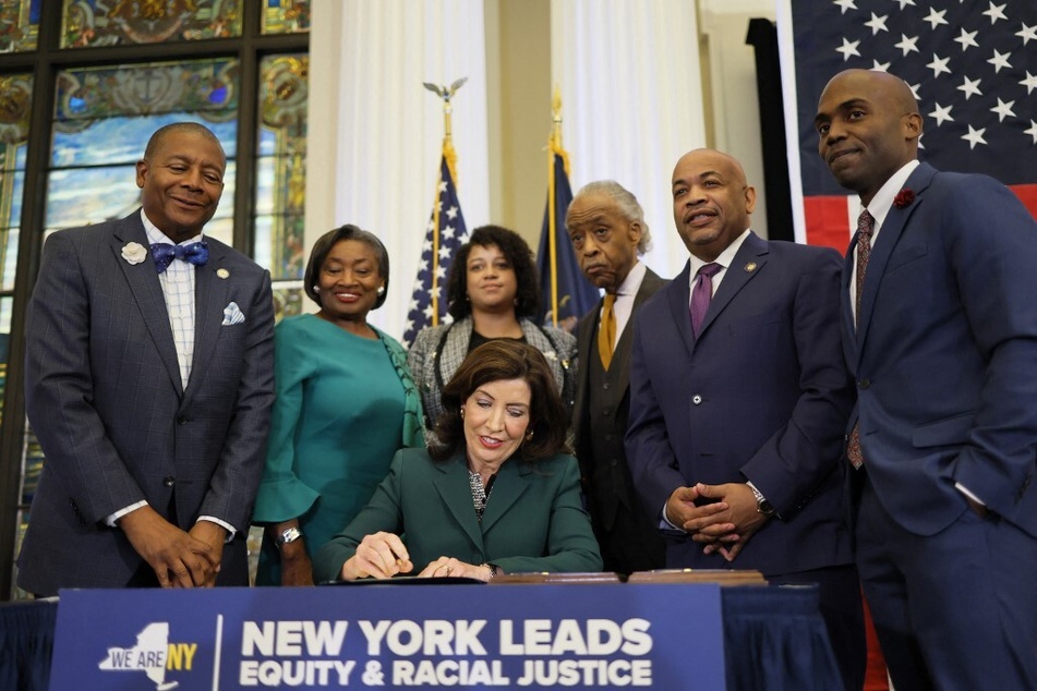 New York Governor Kathy Hochul (c.) signs legislation to create a state reparations commission to address past and present injustice.