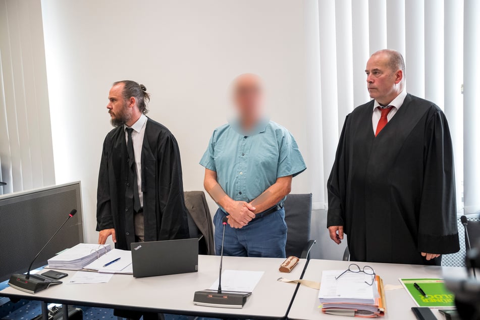 Der Angeklagte (M.) steht zwischen seinen Anwälten Christian Barthelmes (l.) und Thomas Drehsen (r.).