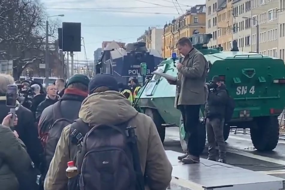 Die bekannte Szenegröße Lutz Giesen verliest die Auflagen. Im Hintergrund hat die Polizei Wasserwerfer und einen Sonderwagen positioniert.