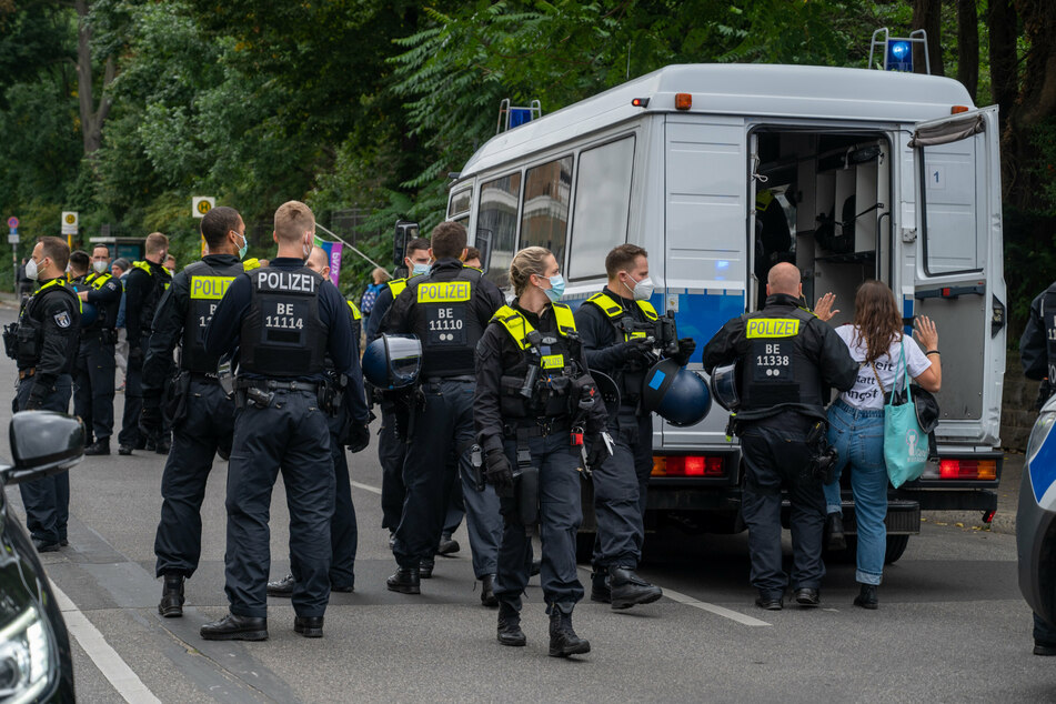 Ein Polizist führt eine Demonstrantin in einen Polizeiwagen, während sich Demonstranten aus Protest gegen die Corona-Politik vor dem Märchenbrunnen in Berlin-Friedrichshain versammeln.
