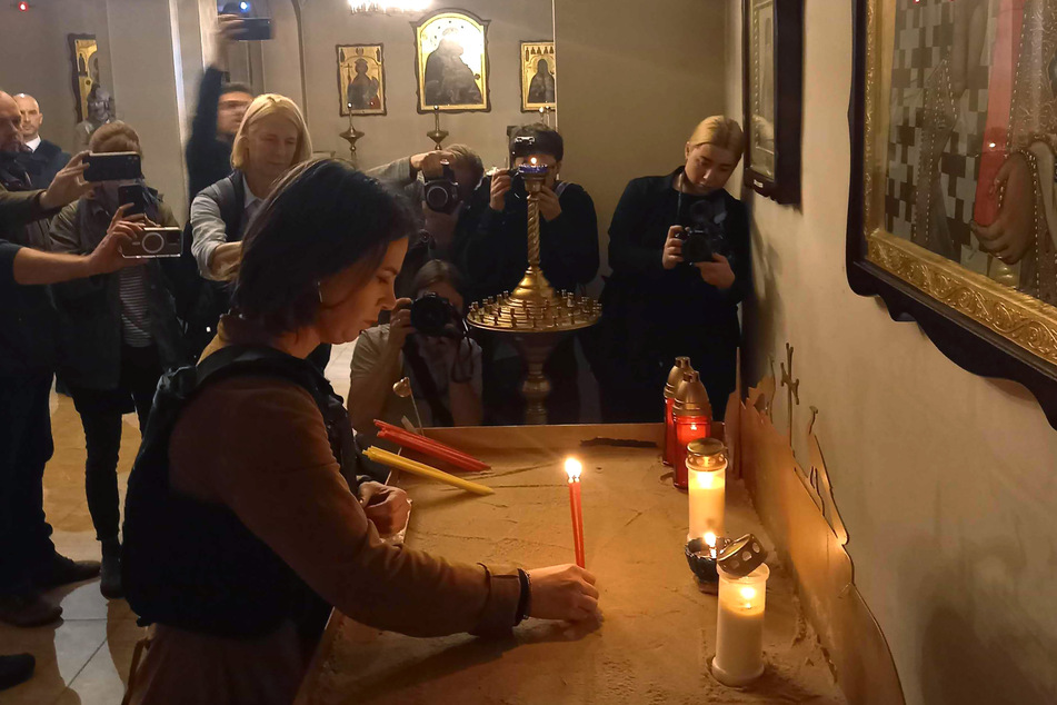 Außenministerin Annalena Baerbock (41, Grüne, M.) entzündet eine Kerze für die Opfer in einer Kirche in Butscha.