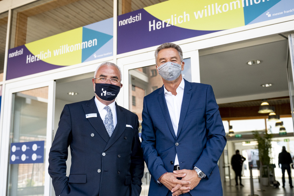 Detlef Braun (r), Geschäftsführer der Messe Frankfurt, und Bernd Aufderheide, Vorsitzender der Geschäftsführung der Hamburg Messe und Congress (HMC), stehen mit Mundschutz vor dem Eingang der Messehallen bei der Eröffnung der Konsumgütermesse "Nordstil".