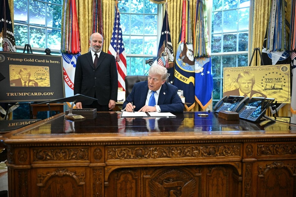 President Donald Trump (r.) speaks signs an executive order in the Oval Office at the White House in Washington, DC, on Friday as Commerce Secretary Howard Lutnick (l.) looks on.