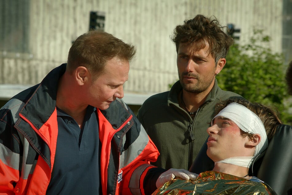 Dr. Haase (Fabian Harloff, l.) ist froh, dass Jason (Frederic Balonier, r.) bei Bewusstsein ist. Paul Kruger (Christian Natter, M.) hat dem Jungen durch sein schnelles Handeln das Leben gerettet.
