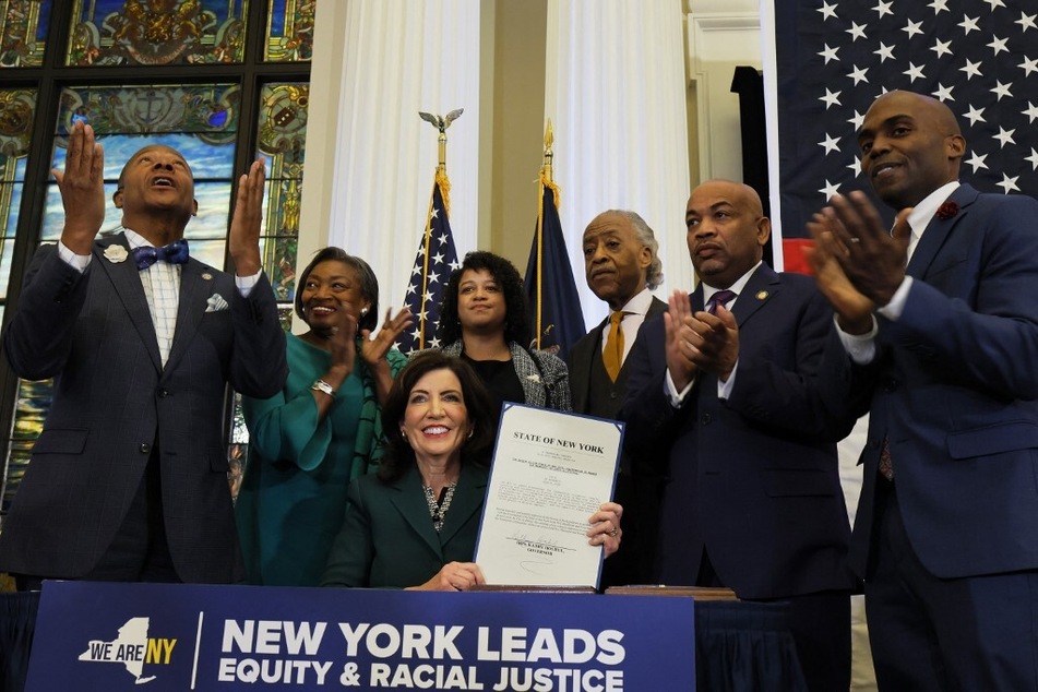 Governor Kathy Hochul holds up signed legislation to create the New York State Community Commission on Reparations Remedies during a ceremony on December 19, 2023.