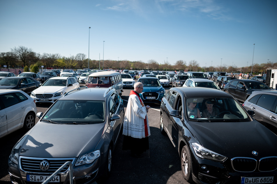 Stadtdechant Pfarrer Frank Heidkamp spricht mit Besuchern des Gottesdienst im Auto.
