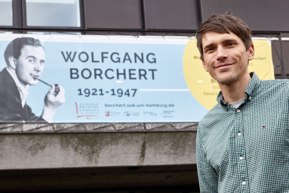 Konstantin Ulmer, Kurator, steht vor der Universitätsbibliothek Hamburg vor einem Banner mit dem Konterfei des Schriftstellers.