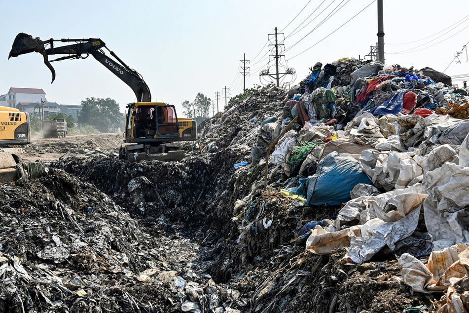 A pile of waste is seen as a worker operates an excavator at a dumping site in Hung Yen province near Hanoi on Thursday.