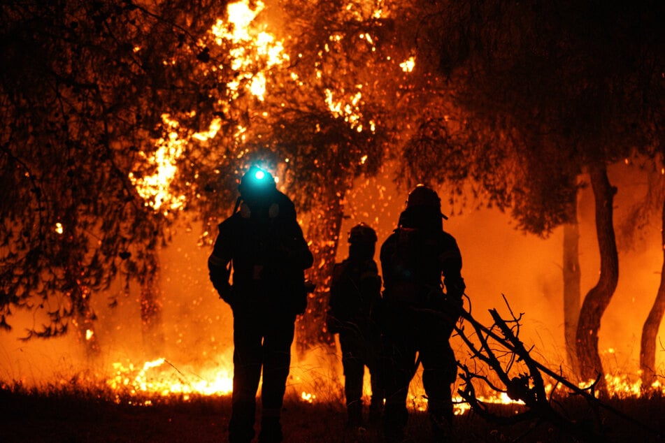 Feuerwehrleute löschen die Flammen während eines Waldbrandes in Asprochori (Oropos).