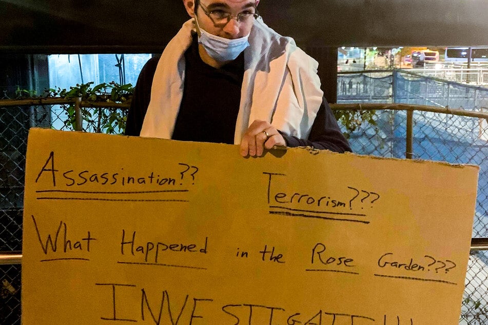 Will, Anhänger von US-Präsident Donald Trump, steht mit einem Schild mit der Aufschrift "Assassination?? Terrorism??? What happened in the rose garden??? Investigate!!!" (Attentat?? Terrorismus??? Was passierte im Rosengarten??? Ermittelt!!!) gegenüber dem Eingang zum Walter-Reed-Militärkrankenhaus.