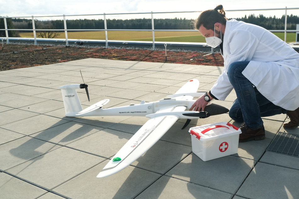 Ein Mitarbeiter des bayerischen Pilotprojektes "MEDinTime" hockt neben einer Drohne, die eilige Medikamente vom Krankenhaus Ingolstadt zu angeschlossenen Kliniken bringen soll.