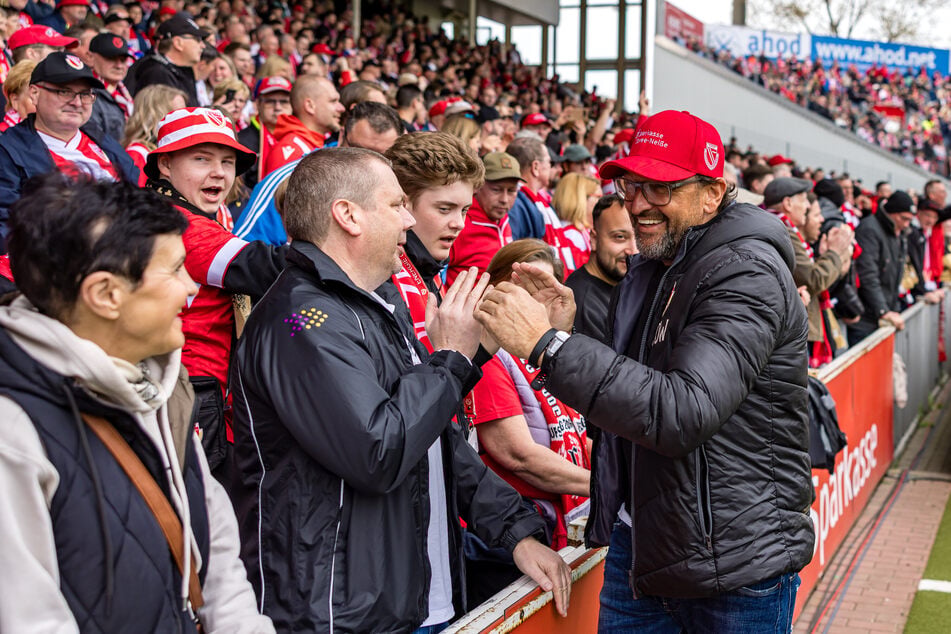 Pele Wollitz (60) klatscht mit den Energie-Fans ab. Vor dem Endspiel in Regensburg erneuert der Trainer ein Versprechen.