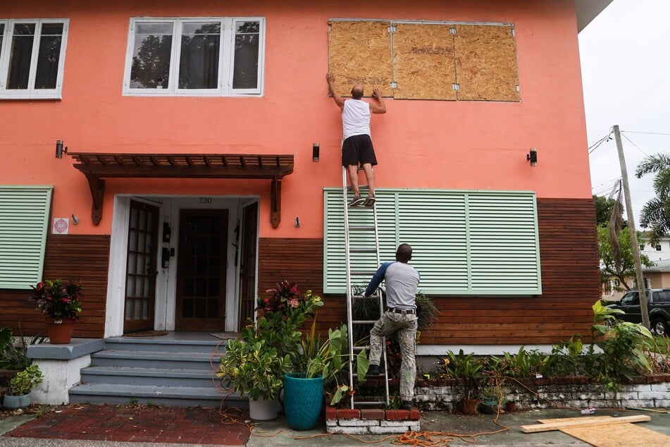 Menschen sichern die Fenster eines Mehrfamilienhauses in St. Petersburg.