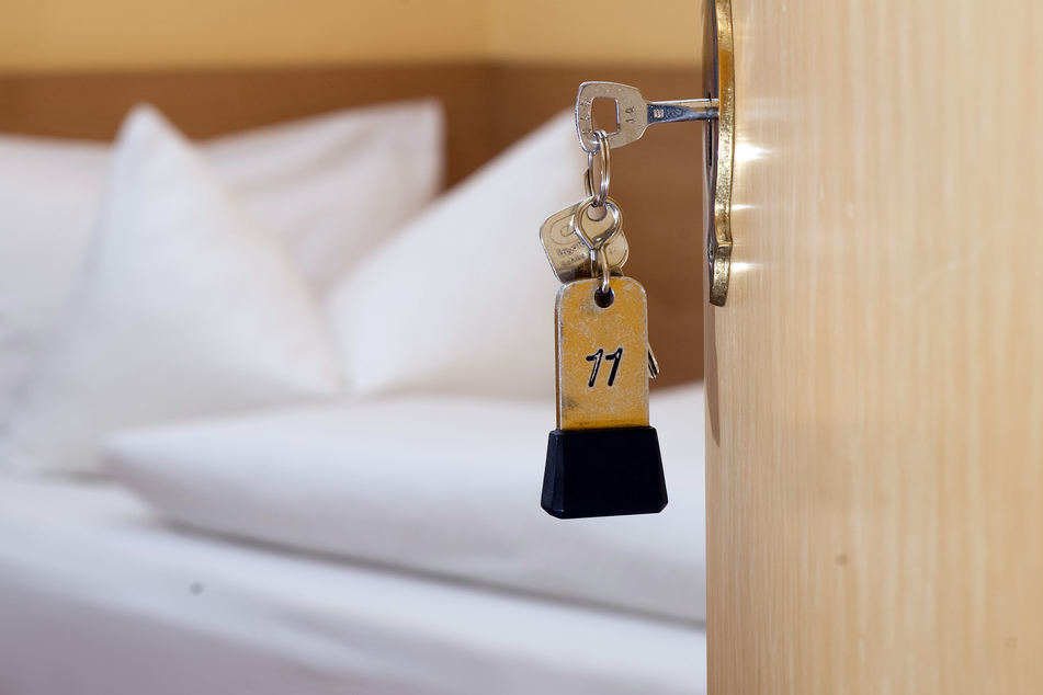 Ein Zimmerschlüssel hängt in der Tür eines Hotelzimmers.
