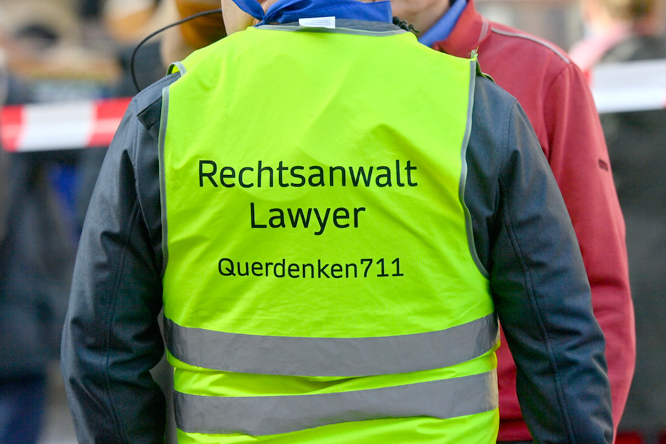 Ein Demonstrant trägt in München eine Sicherheits-Warnweste mit der Aufschrift "Rechtsanwalt - Lawyer - Querdenker 711". Maßnahmen-Gegener hatten in Bayern erneut geklagt.