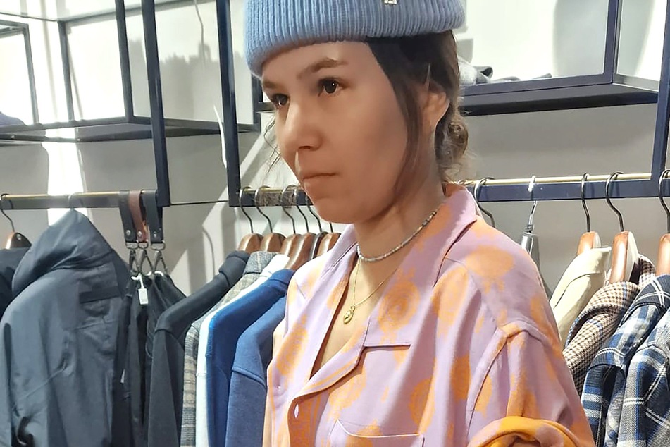 Miri (30) shoppt im ersten Laden ein Hemd in den Farben Flieder und Orange.