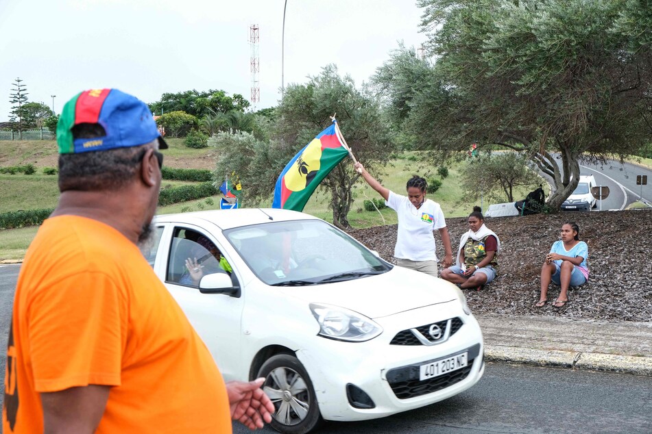 Ein Demonstrant schwenkt eine Fahne der sozialistischen Nationalen Befreiungsfront der Kanaken (FLNKS) an einem Fahrzeugkontrollpunkt in Nouméa inmitten von Protesten.