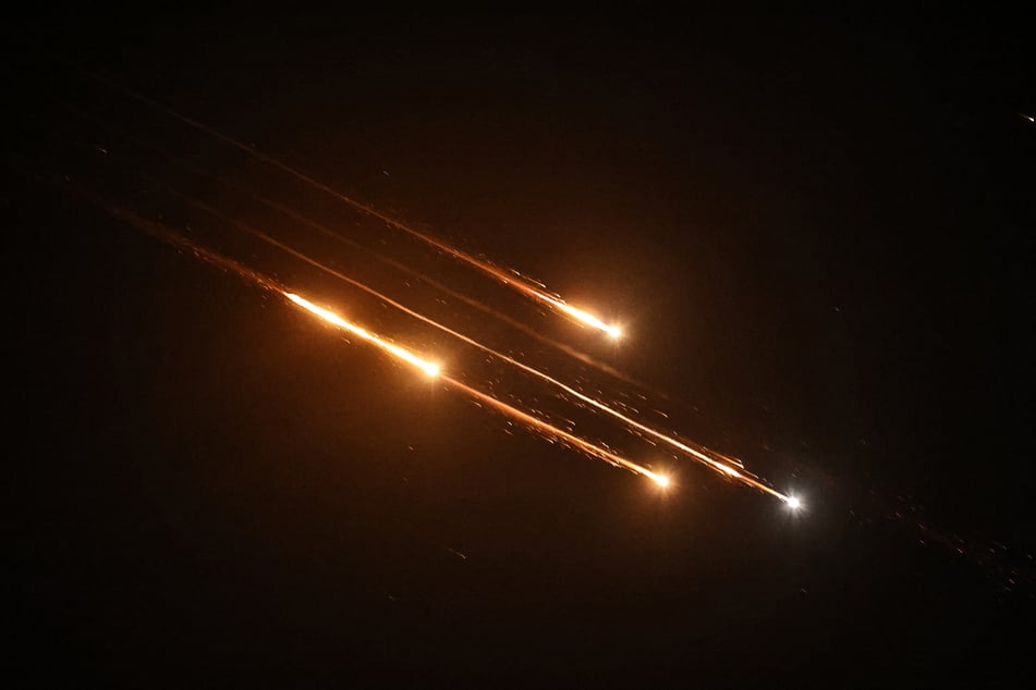 Debris of missiles fired from Iran toward Israel leave trails in the night sky over Nablus in the occupied West Bank after being intercepted on Friday.