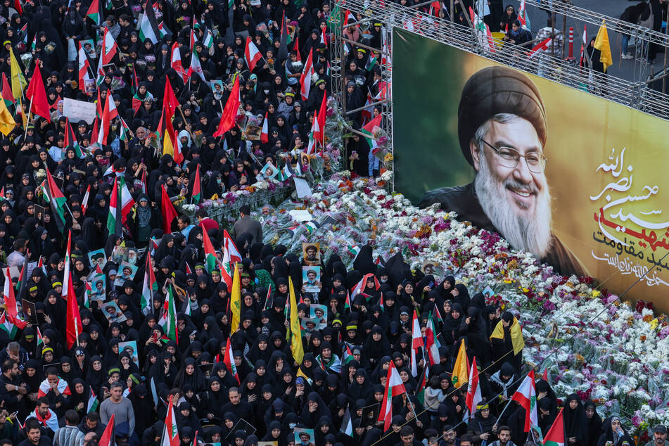 Iranians lay flowers beneath a billboard bearing a portrait of Hezbollah leader Hassan Nasrallah, who was killed in an Israeli air strike on Beirut's southern suburbs on September 27, during an anti-Israel protest in Palestine Square in Tehran on September 30, 2024.