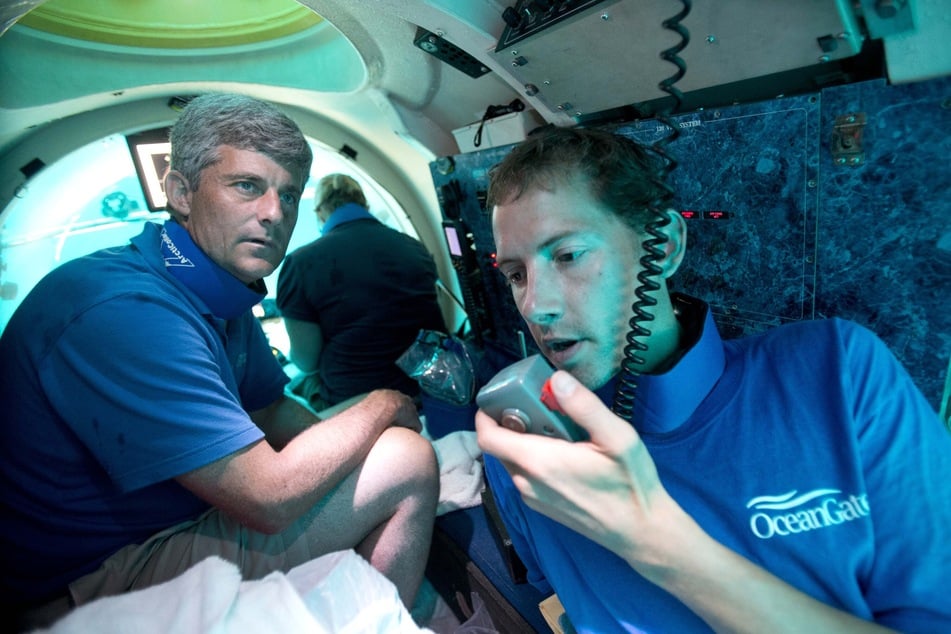 Tauchbootpilot Randy Holt (r.) kommuniziert mit dem Begleitboot, während er und Stockton Rush (l.) sich mehrere Meilen unter der Meeresoberfläche befinden. Bei einem Systemausfall wäre die Benachrichtigung viel zu spät gekommen.